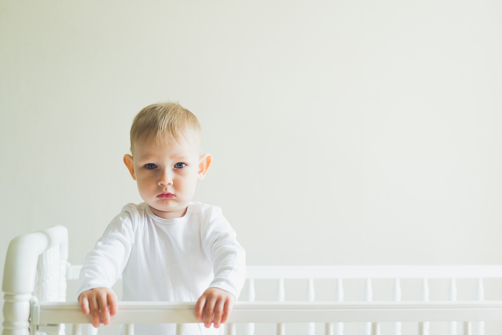 The child is standing up in his crib.
